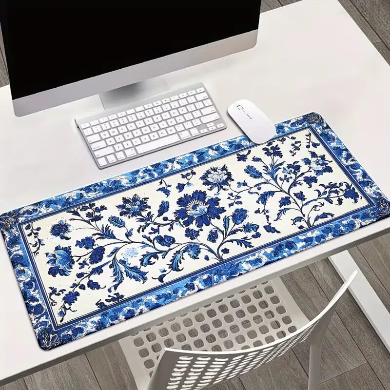 A blue and white floral patterned gaming mouse pad with a non-slip rubber base is displayed on a white desk.