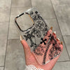A hand holds a clear holographic gradient phone case featuring intricate black gothic and religious symbols.