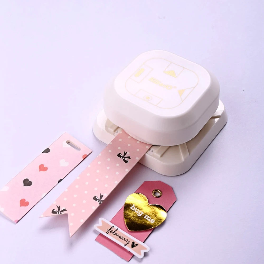 A white crafting tool featuring a tag punch corner rounder and a heart-shaped tag with a February message.