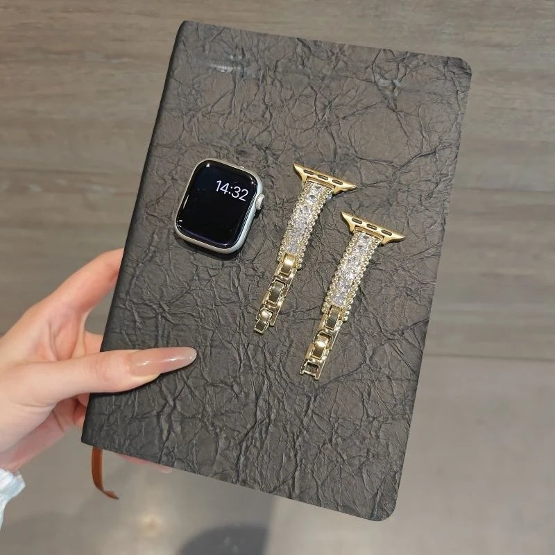 A black leather card features a smartwatch and two gold-toned crystal-embellished watch straps.