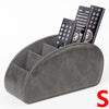 A grey PU leather remote control holder with five compartments displaying various electronic devices.