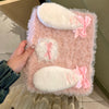 A pink fluffy rabbit plush case with white accents is shown resting on a light-colored surface.
