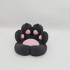 A black 3D printed cat paw phone stand with an anti-slip base featuring pink details.