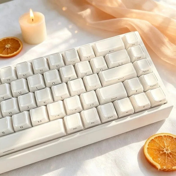 A white mechanical keyboard with crystal jelly side-printed keycaps is shown on a light surface next to an orange slice and a