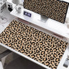 A large leopard print desk pad featuring brown and black spots is displayed on a white desk.