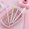 A pink woven basket holds several cute cartoon fruit gel pens in various pastel colors on a pink background.