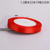 A roll of red satin ribbon with a white center core is shown on a white surface.