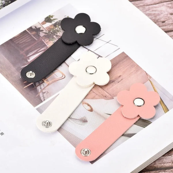 Three leather flower cable organizers in black, cream, and pink are displayed on a white background.