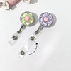 A pair of clear retractable ID badge holders with floral pull buckles, featuring light green and pink flowers.