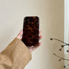 A hand holds an Amber Retro Shockproof Phone Case for iPhone with a leopard print design.