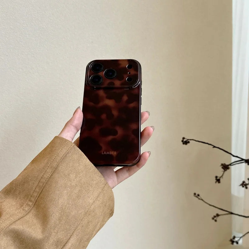 A hand holds an Amber Retro Shockproof Phone Case for iPhone with a leopard print design.
