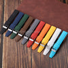A collection of colorful perforated silicone watch straps laid out on a brown surface.