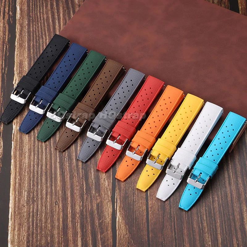 A collection of colorful perforated silicone watch straps laid out on a brown surface.