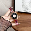 A hand holds a resin beaded watch with a pink and black design against a blurred background.