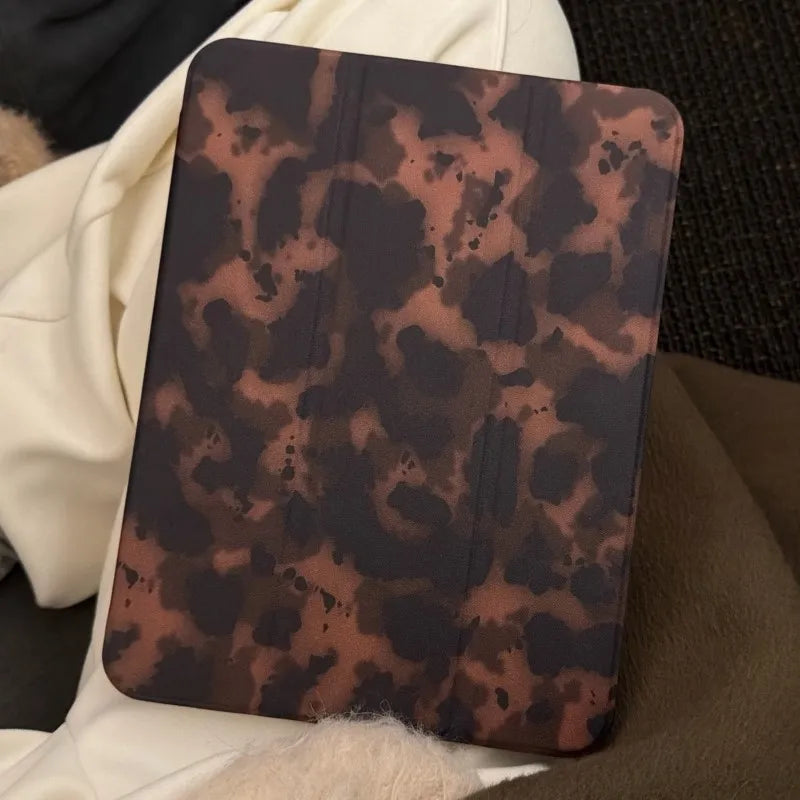 Dunkelbraunes Leopardenmuster-Leder-Tablet-Cover auf einer weichen weißen Decke.