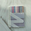 A stack of A6 sticky note notebook featuring various colored stickers and a purple geometric design.
