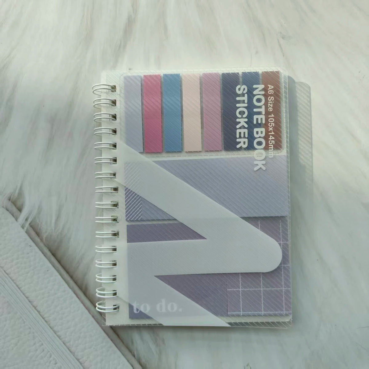 A stack of A6 sticky note notebook featuring various colored stickers and a purple geometric design.