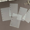 A set of ten transparent divider pages for loose-leaf planners, lying on a gray surface.