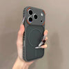 A hand holds a dark gray frosted magnetic silicone case for an iPhone, displaying the back and camera module.