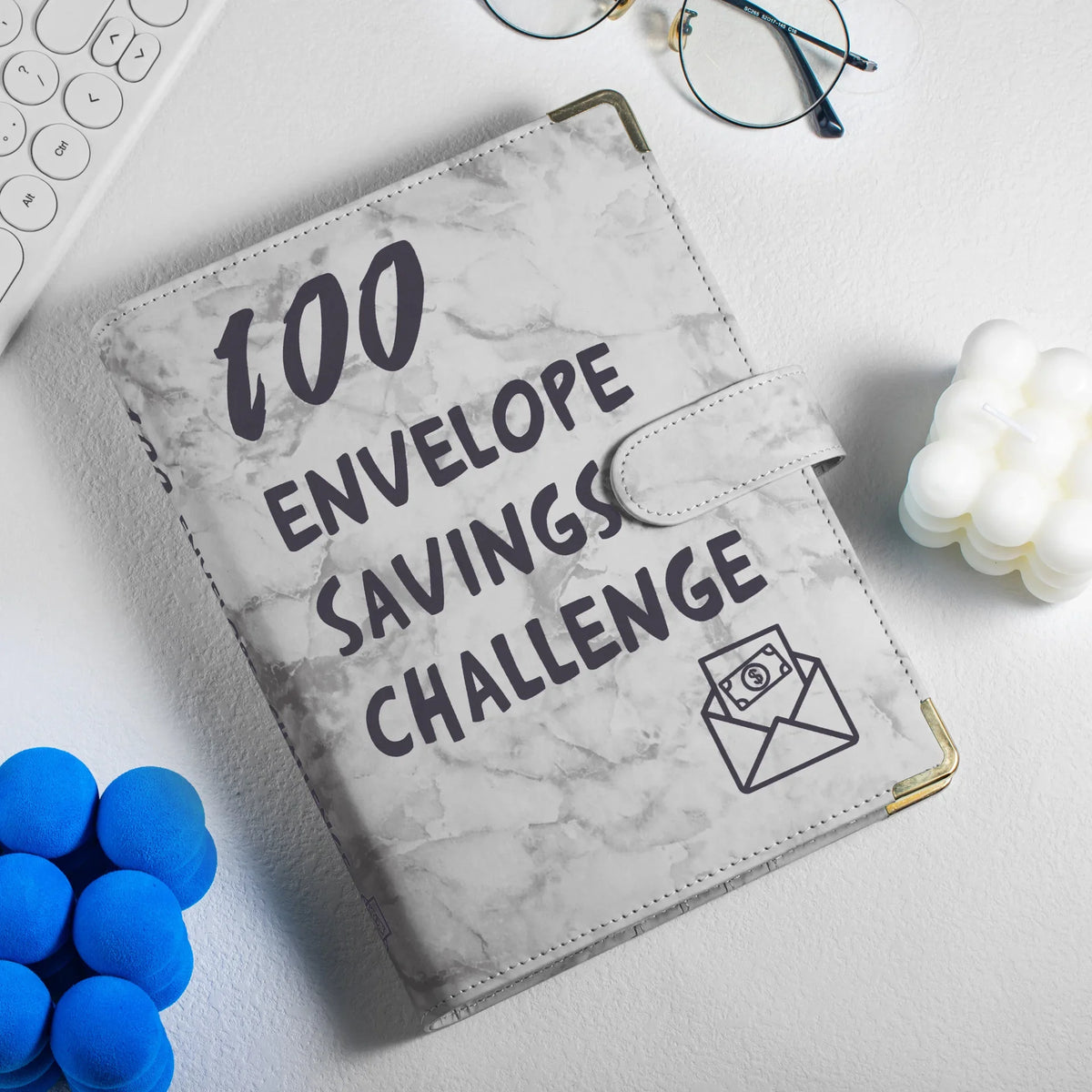 A marble-patterned A5 budget binder with a clear pocket and an envelope icon resting on a white surface.