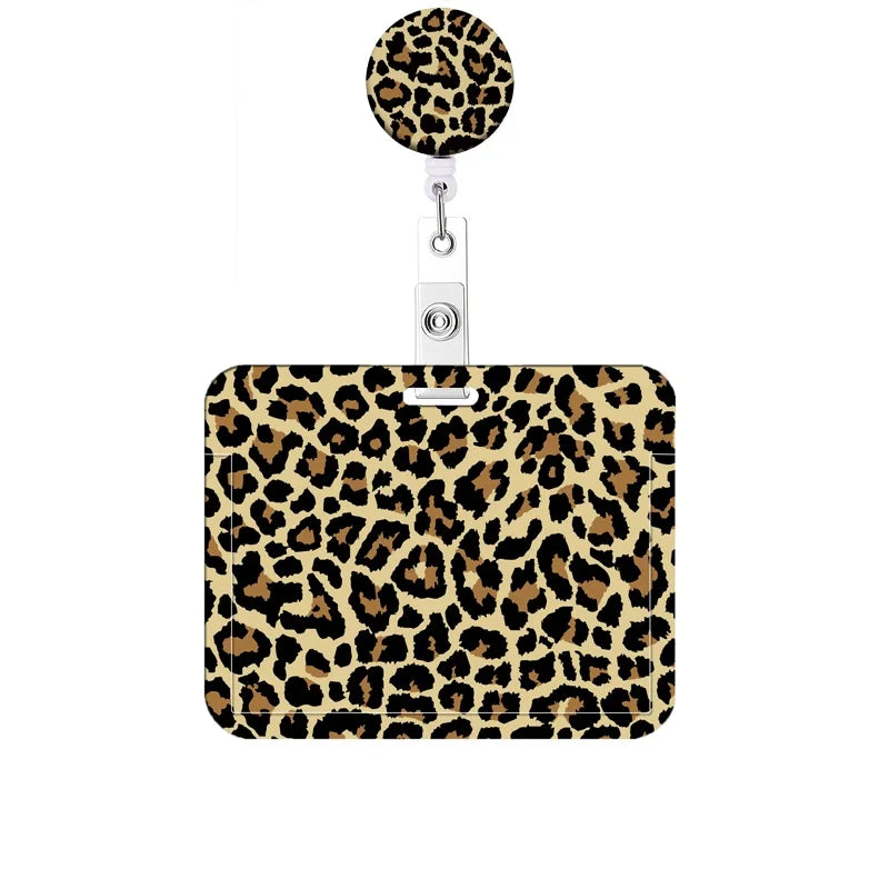 A leopard print retractable badge holder with a round charm attached.