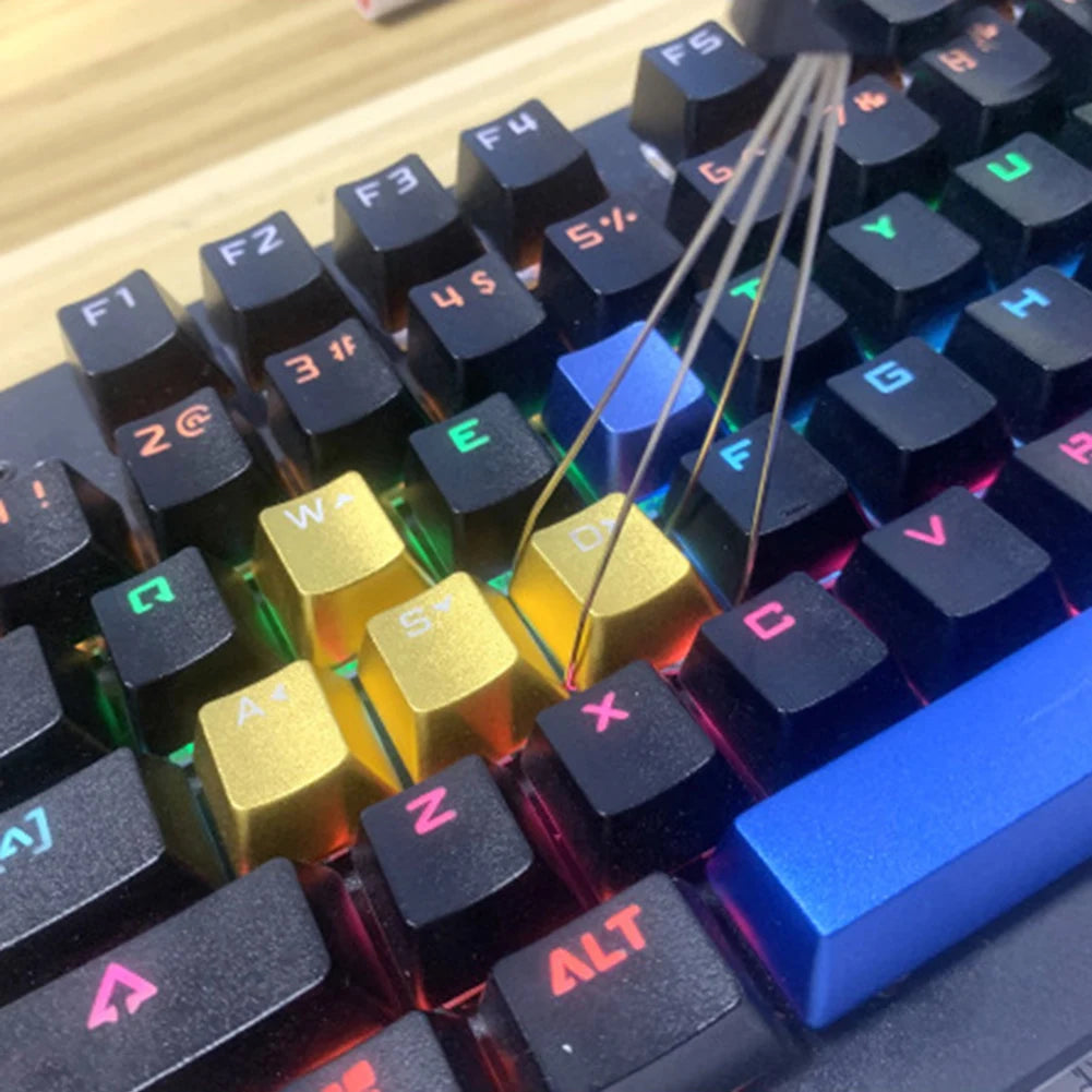 Close-up view of a mechanical keyboard showing keycaps being pulled off with a thin metal tool.