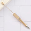 A gold-colored DIY beadable pen is shown lying on a white tiled surface.