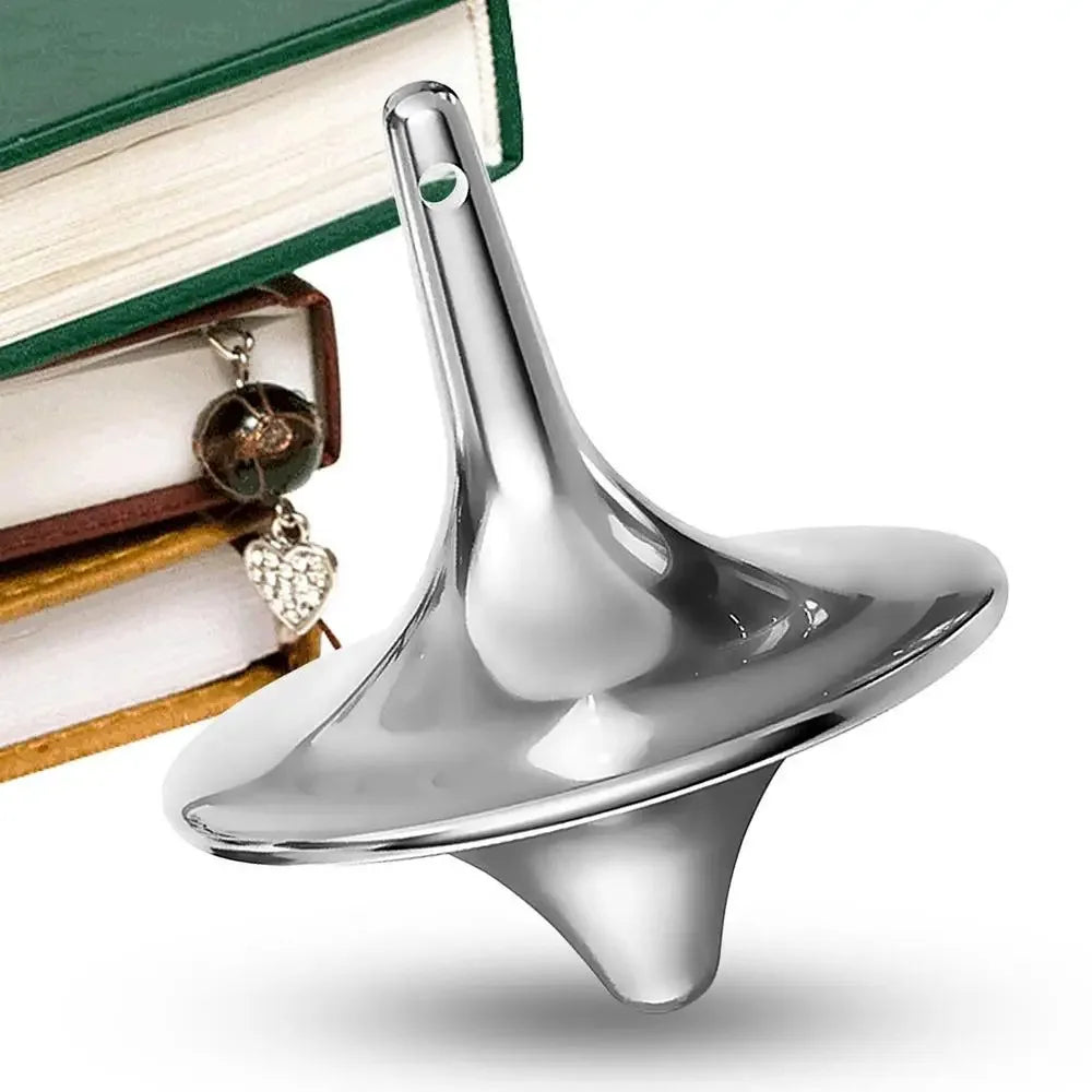 A silver metal hand spinning top fidget toy resting on a stack of books.