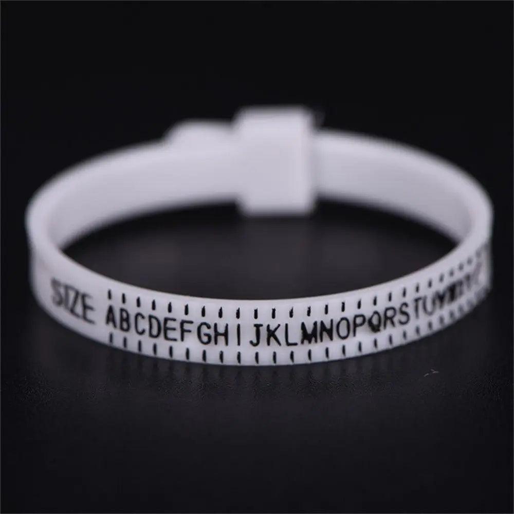 A white precision ring sizer tool with a finger ring and letter markings is shown on a dark surface.