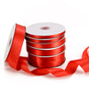 A stack of red satin ribbon spools with a roll unwound and a ribbon draped out.