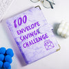 A purple marble budget binder titled 100 Envelope Savings Challenge resting on a white surface.