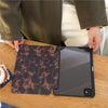 Dunkelbraunes, gemustertes Leder-Tablet-Cover neben einem Apple iPad auf einer Holzoberfläche