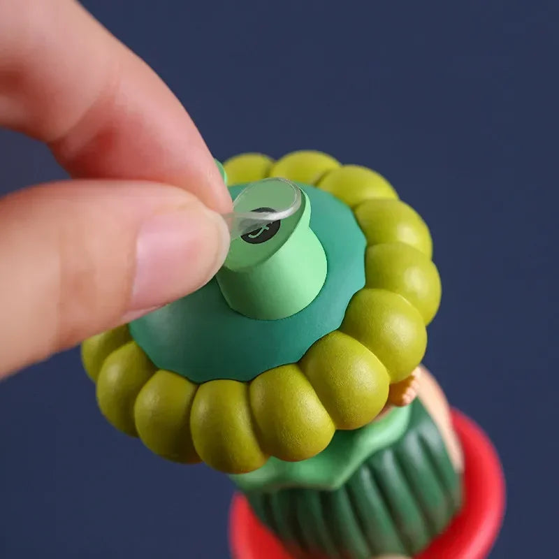 A hand is applying a clear adhesive fixer pad to a green and yellow product component.