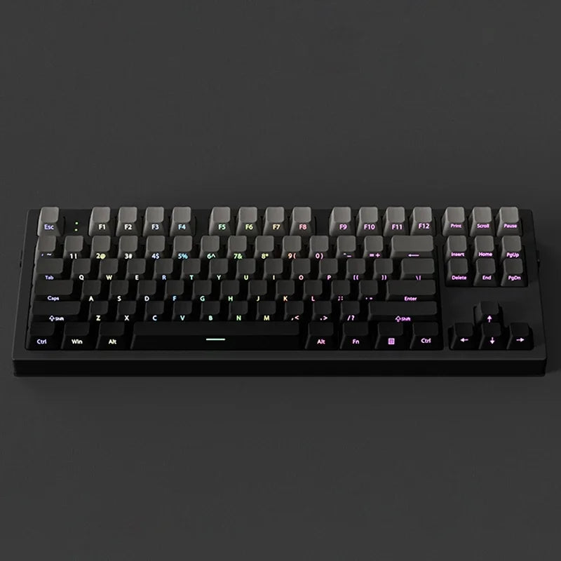 A close-up view of a black mechanical keyboard with gradient gray double shot PBT keycaps and side printing.