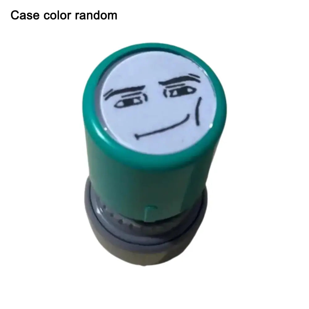 A rubber stamp with a funny meme face design and a green ink pad.