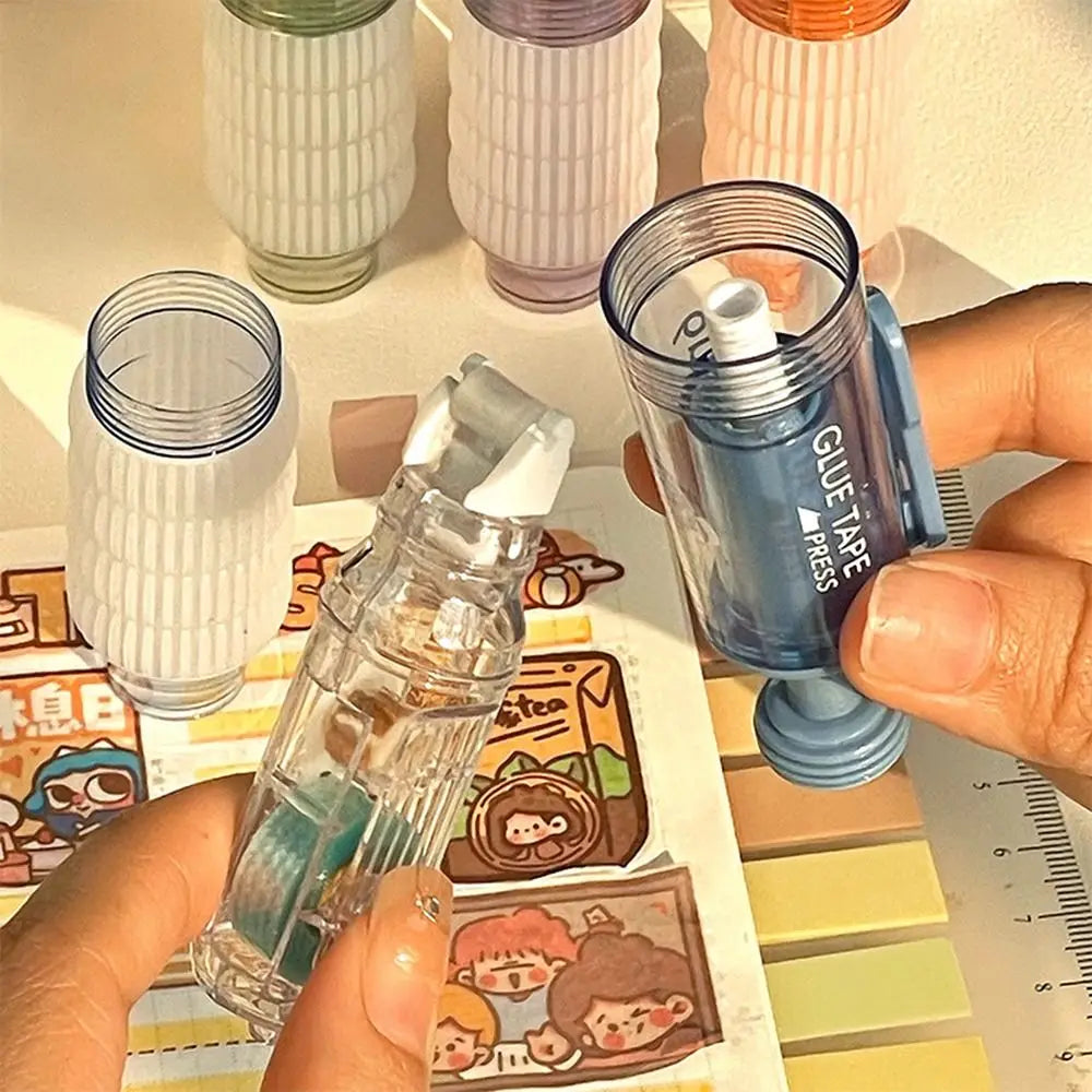 A hand holds a clear glue pen with blue glue tape and a white tip next to various colored glue dots.