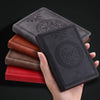 A hand holds a stack of retro PU leather pocket notebooks in shades of brown, red, and black.