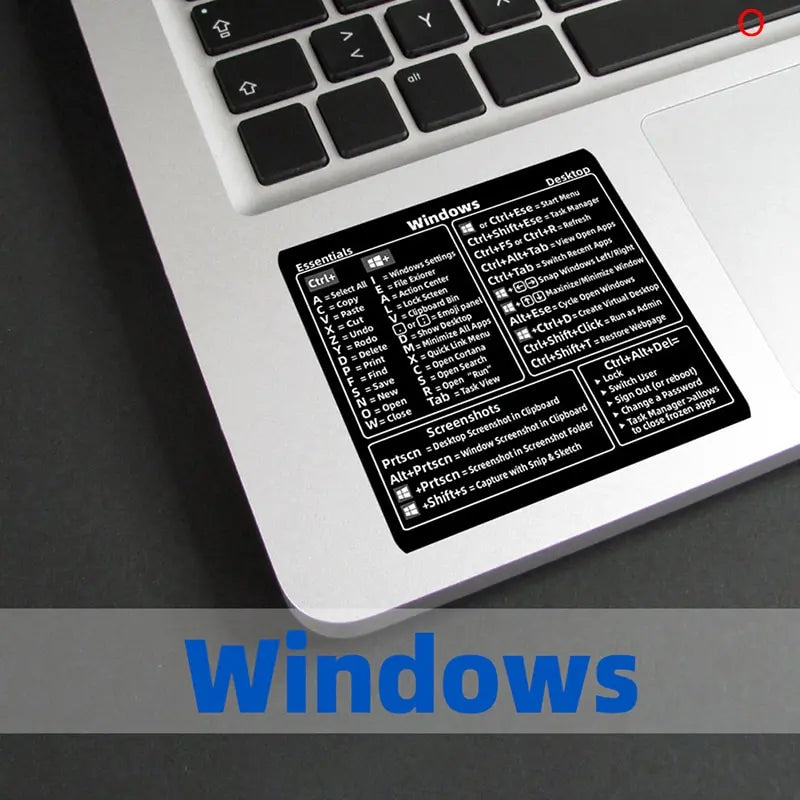 A close-up view of a laptop keyboard displaying a Windows shortcut quick reference sticker.