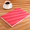 A red notebook titled VOETBOOK is placed next to a white cup and saucer on a wooden surface.