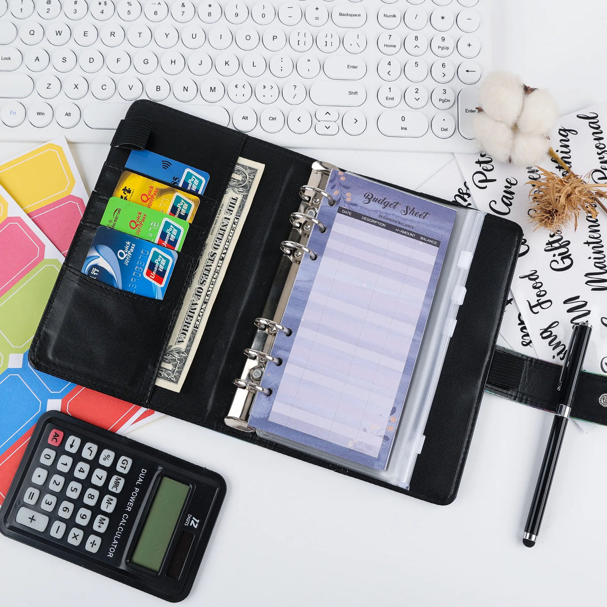 Un set d'organisateur de budget et de liquide noir avec une feuille, une calculatrice et un stylo sur un fond blanc.