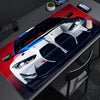 A large non-slip gaming mouse pad featuring a detailed racing car design on a red surface.