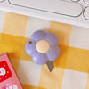 A purple cat paw mini cutter with a light yellow blade rests on a yellow and white checkered surface next to a pink box.