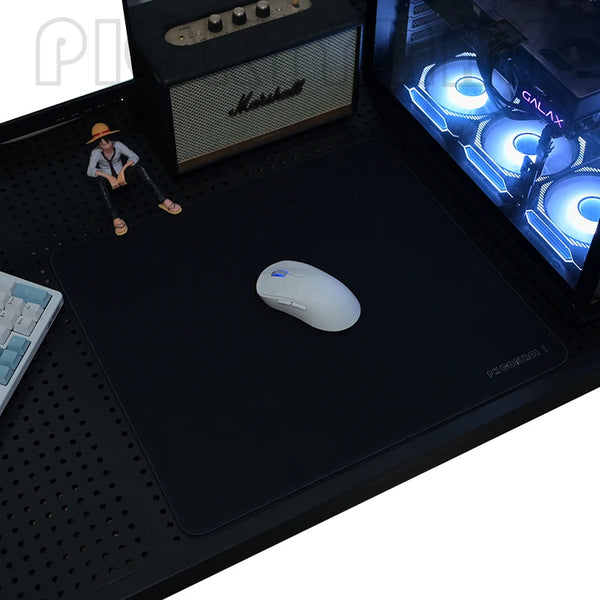 A black gaming mouse pad is shown with a white computer mouse and a small figure on a desk mat.