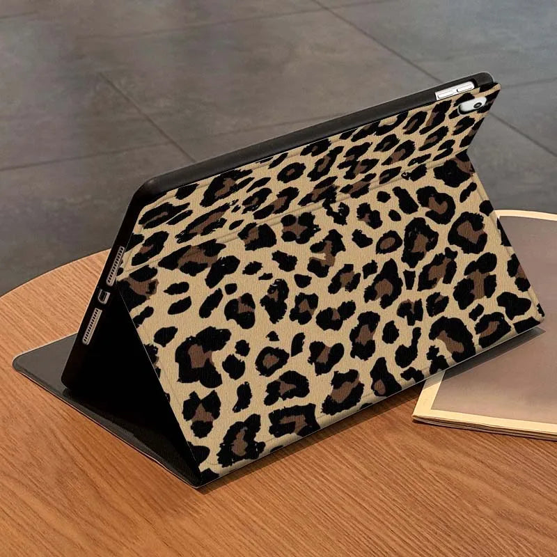 A black protective skin with a leopard print pattern for an iPad case is shown on a wooden surface.