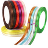 A collection of satin ribbons in various colors including red, orange, purple, and green, displayed on a spool.
