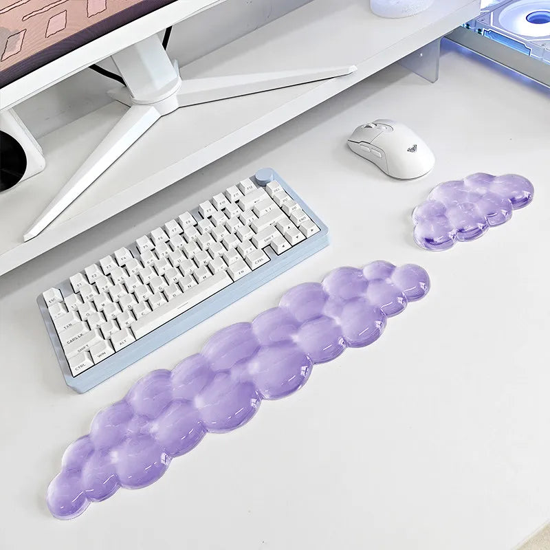 A purple ergonomic cloud wrist rest designed for keyboard and mouse use, shown next to a computer setup.