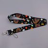 Black lanyard featuring a repeating pattern of rainbow stripes, fruit, and geometric shapes.