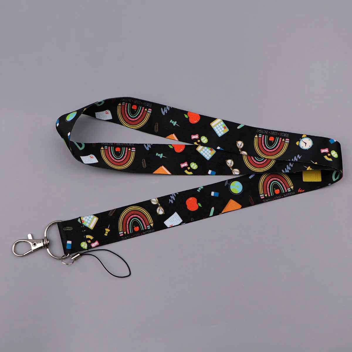 Black lanyard featuring a repeating pattern of rainbow stripes, fruit, and geometric shapes.