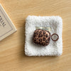 A leopard print earphone case cover rests on a white fluffy towel.