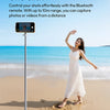 A woman stands on a beach using an Ulanzi automatic phone tripod and Bluetooth remote to take photos or videos.